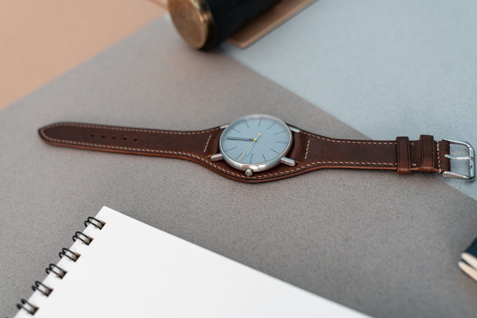 Cognac Bund strap and pale-dial watch laid flat across a grey work surface.