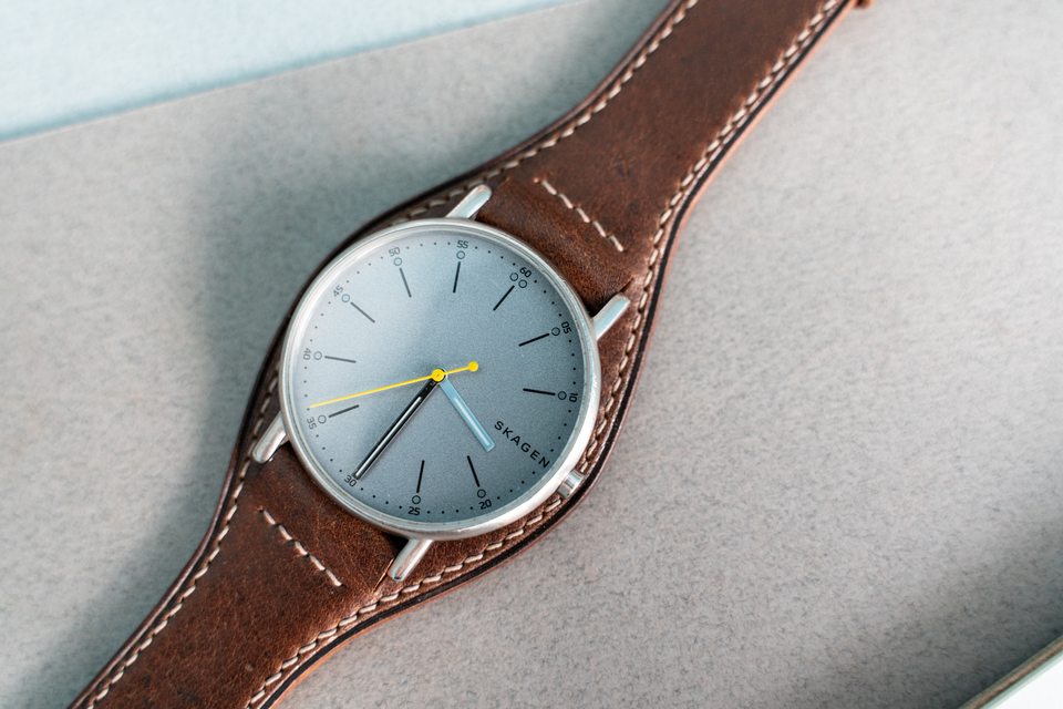 Close view of the pale watch dial, cognac leather surround and light stitching.