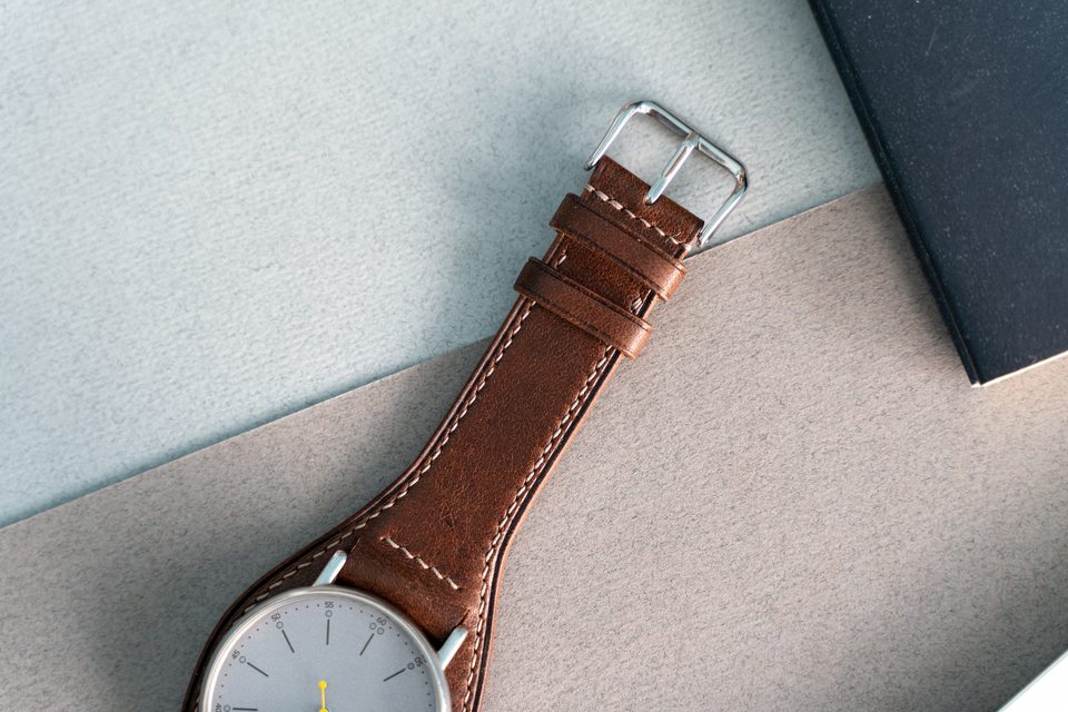 The cognac strap from its silver-coloured buckle to the fitted watch.