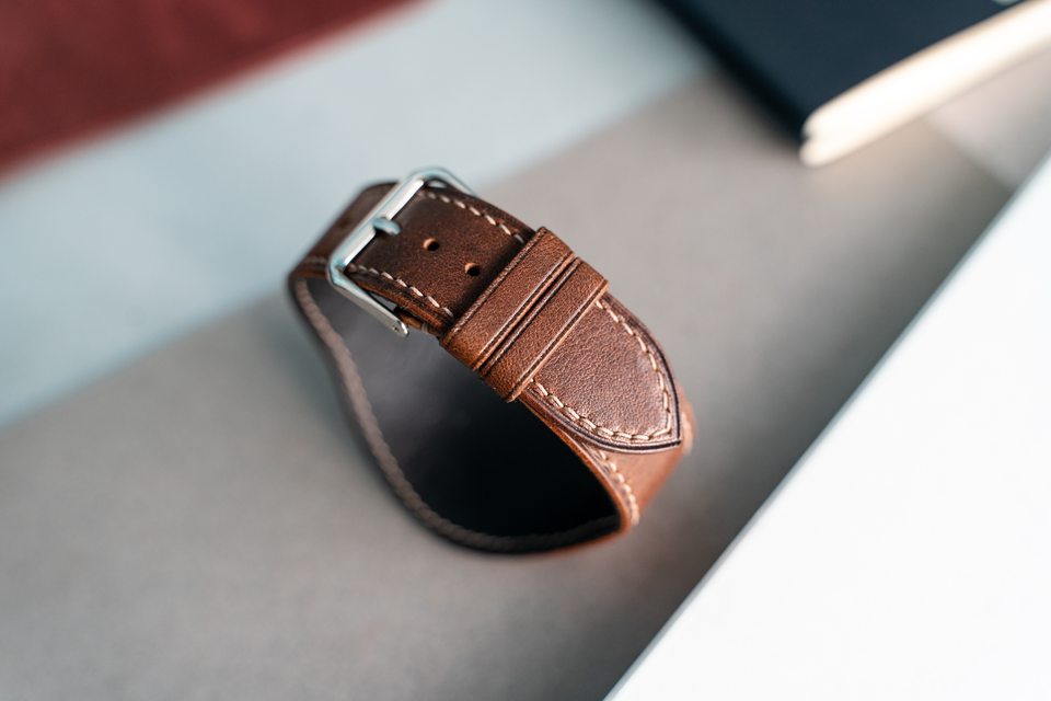 The cognac strap fastened into a loop, with buckle and keepers in view.