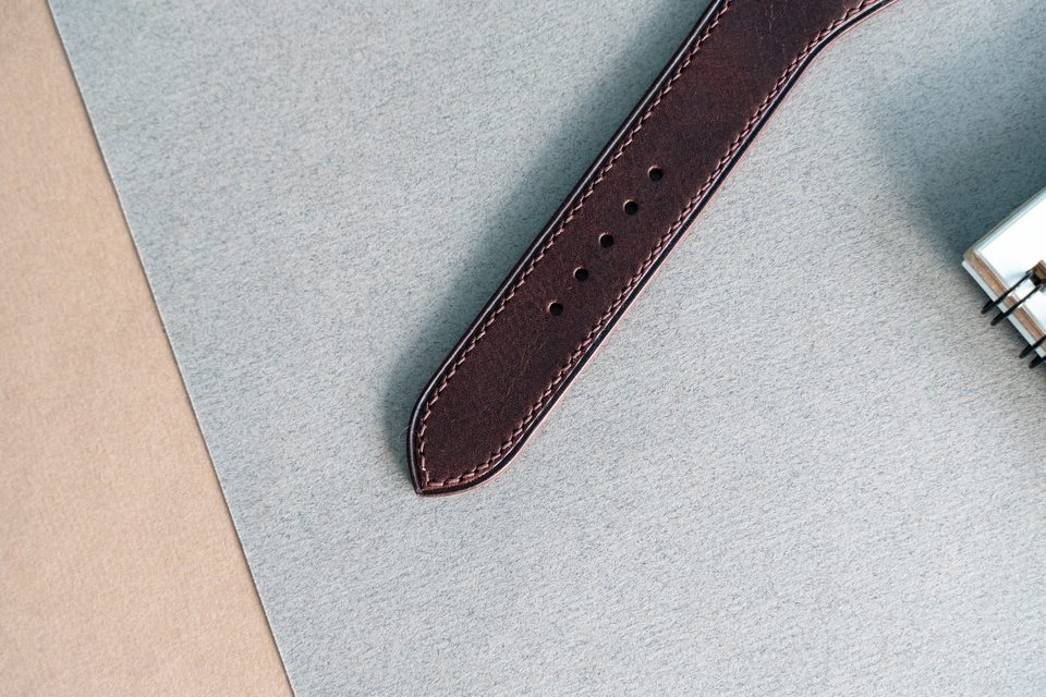 Dark brown pointed strap end, adjustment holes and contrasting stitches.