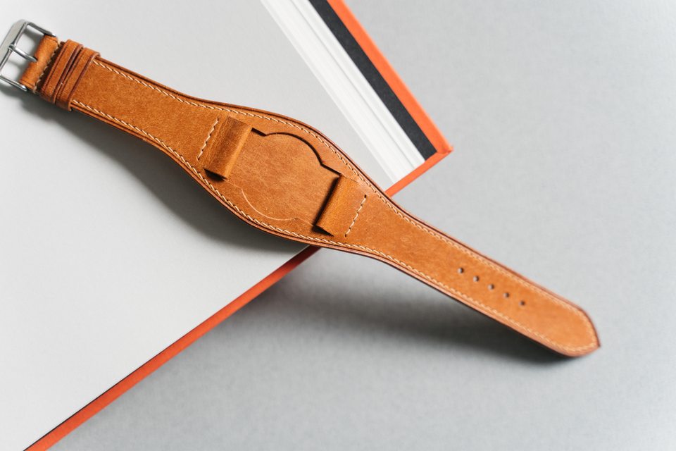Golden tan Bund strap laid diagonally across the corner of an open book.