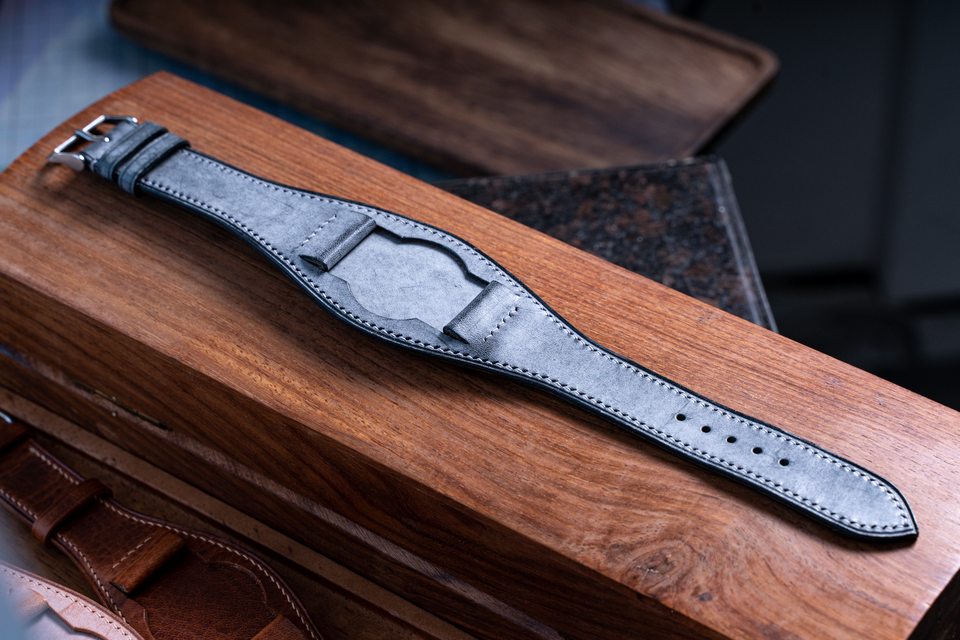 Grey mottled Bund strap laid across a long wooden tray.