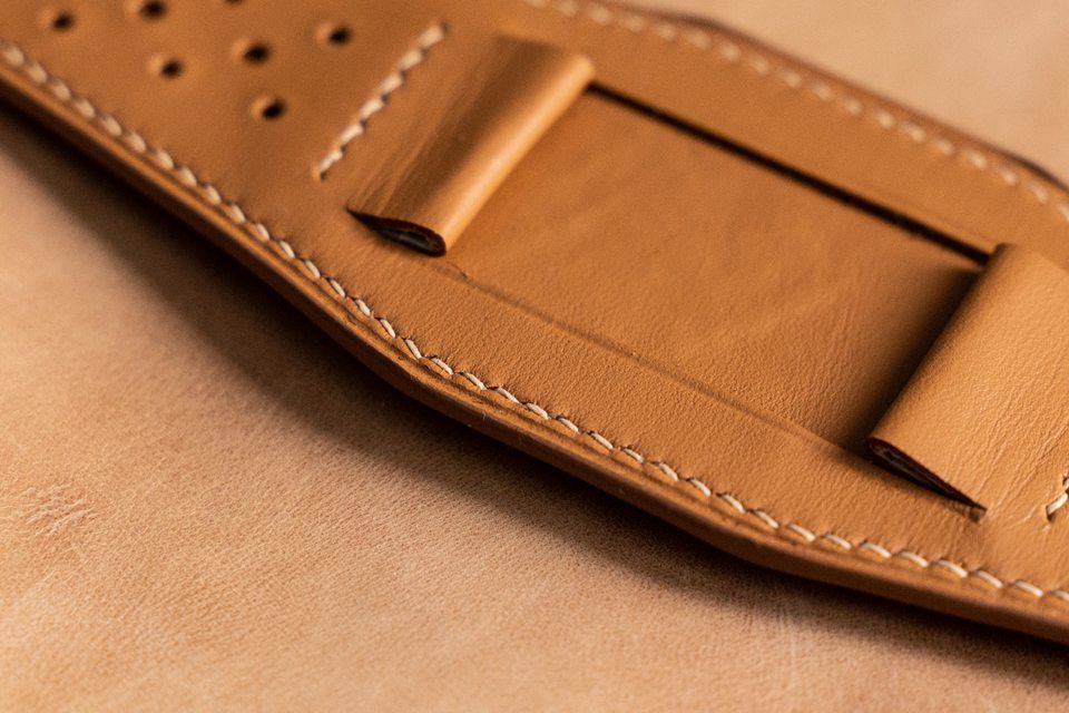 Close-up of grouped holes, light stitching and a folded attachment on the tan pad.