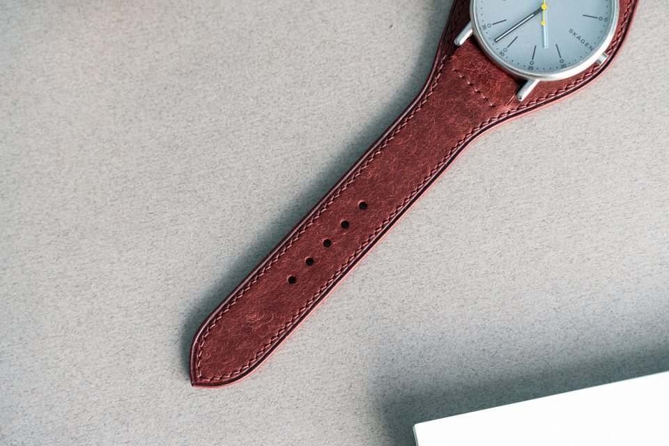 The red strap taper, adjustment holes and part of the fitted watch in close-up.