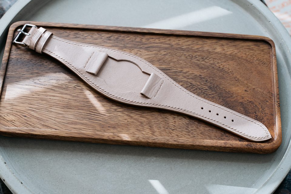 Full pale stone Bund strap laid flat on a wooden tray.