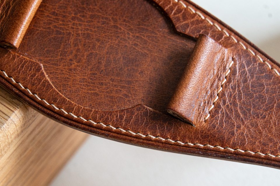 Close view of the cognac centre pad, irregular grain and pale stitches.