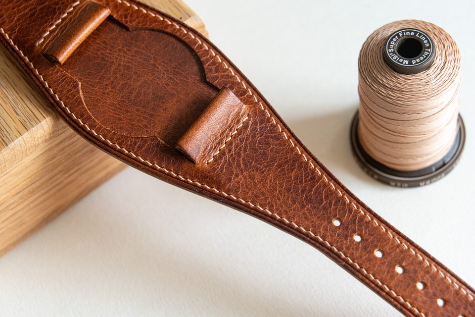 Cognac Bund centre and folded watch attachments beside a thread spool.