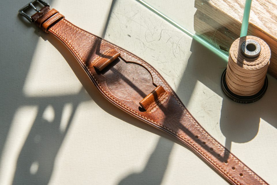 Full cognac Bund strap in angled daylight beside a spool of thread.