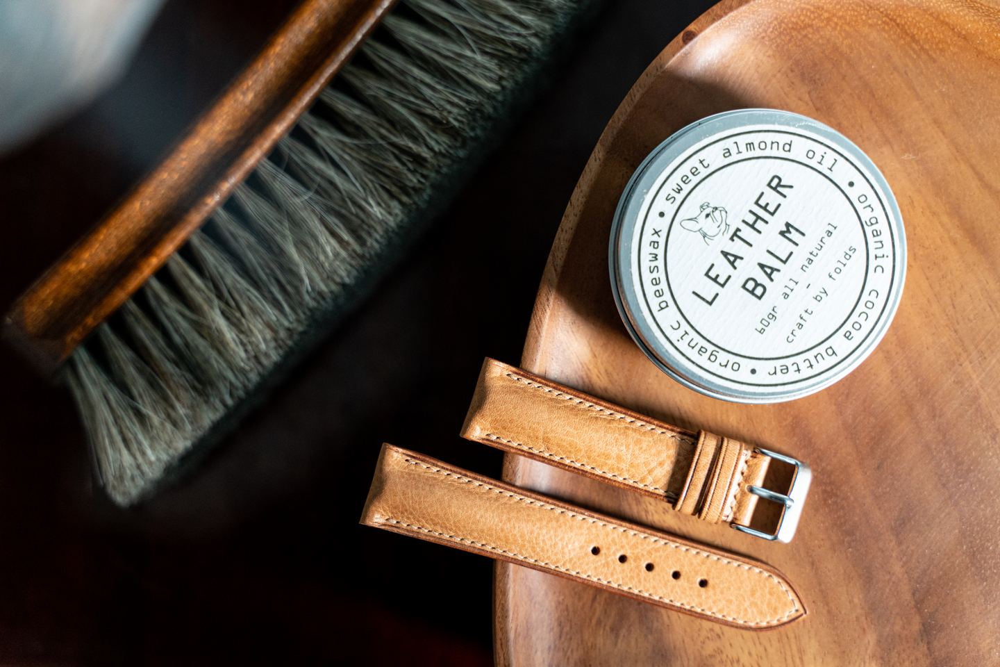 Horsehair brush and leather balm beside a finished strap